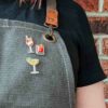 Cocktail pin badges on a bartender apron