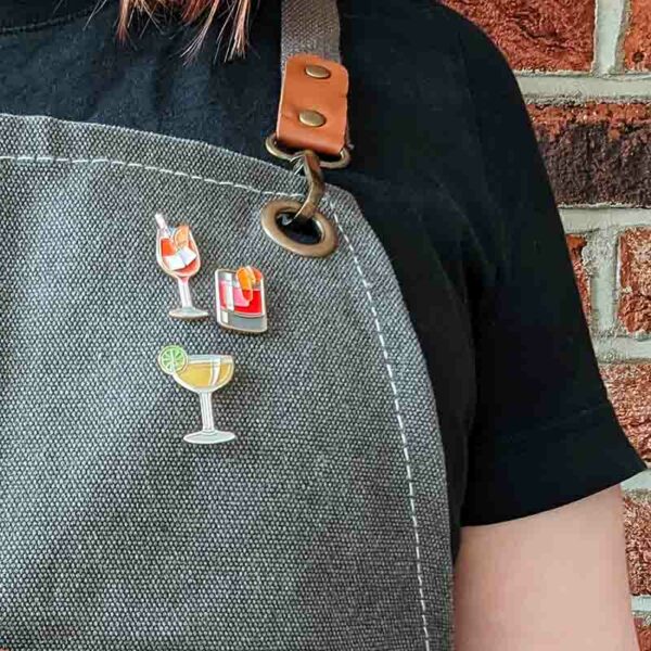 Cocktail pin badges on a bartender apron