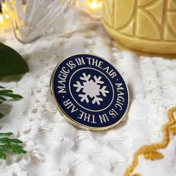 Magic is in the air - text with a snowflake image on round pin badge